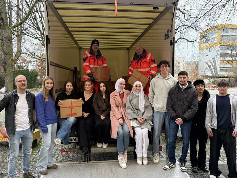 Schüler und Lehrkräfte verladen Pakete in einen Lastwagen der Johanniter